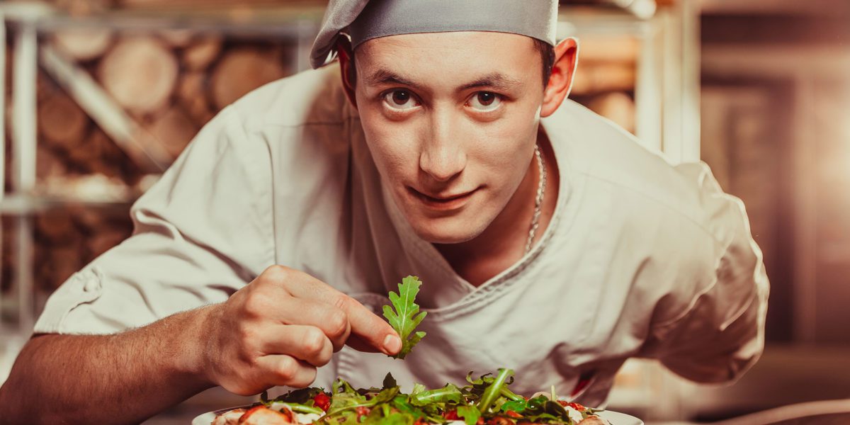 pizzaiolo che condisce una pizza