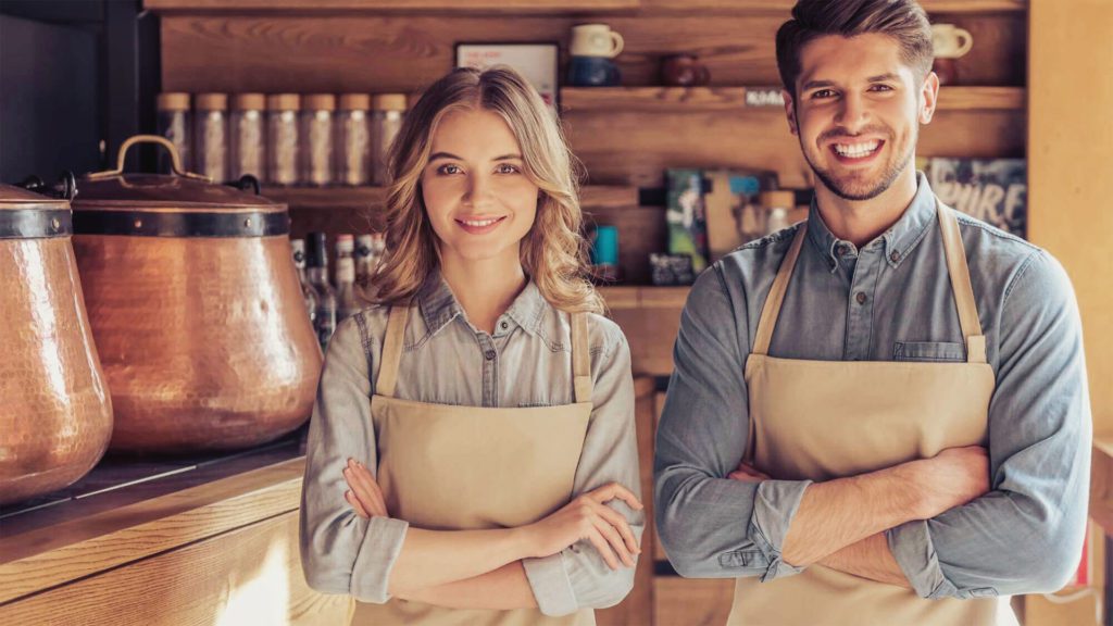 due camerieri che sorridono all'interno di un bar