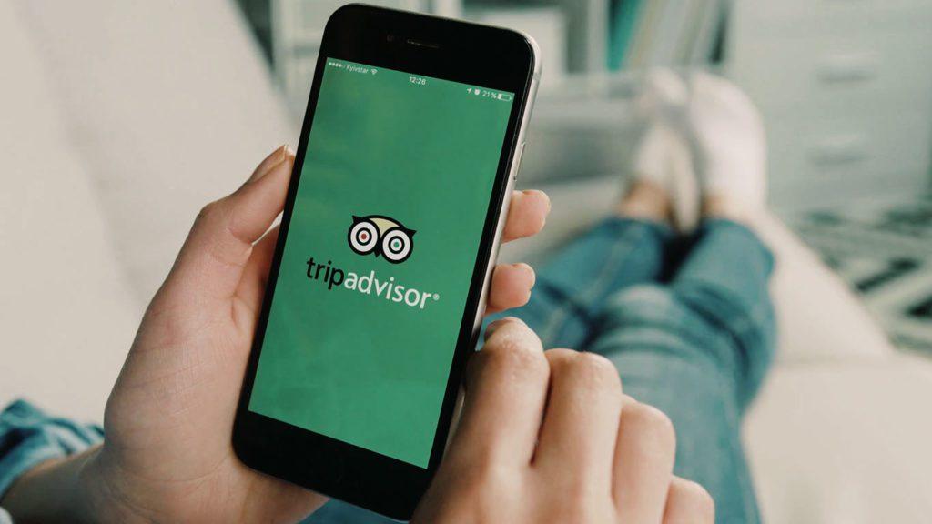 ragazza che utilizza l'app di TripAdvisor sul suo smartphone